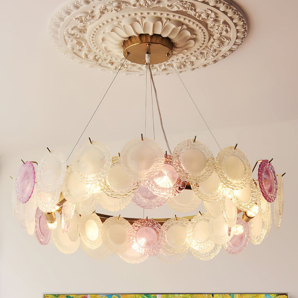 A two-row Clérachic pendant of pink and frosted glass discs below a carved ceiling rose, glowing warm.