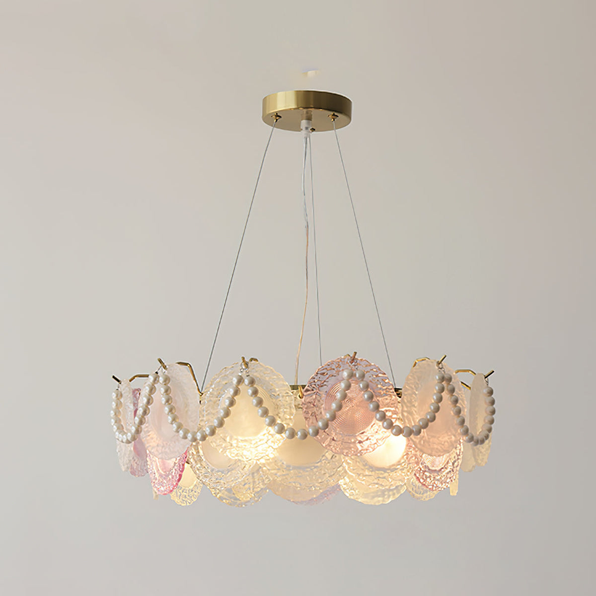 This Clérachic pendant with looped pearls hangs in a plain room, its rim of pink and frosted glass discs lit from inside.