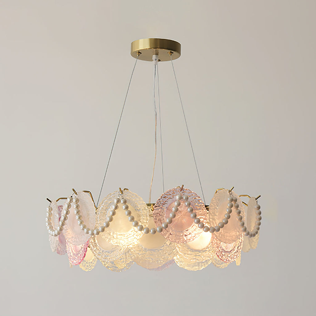 Clérachic pendant with pearl swags across the discs, lit, on a brass canopy against a grey-beige wall.