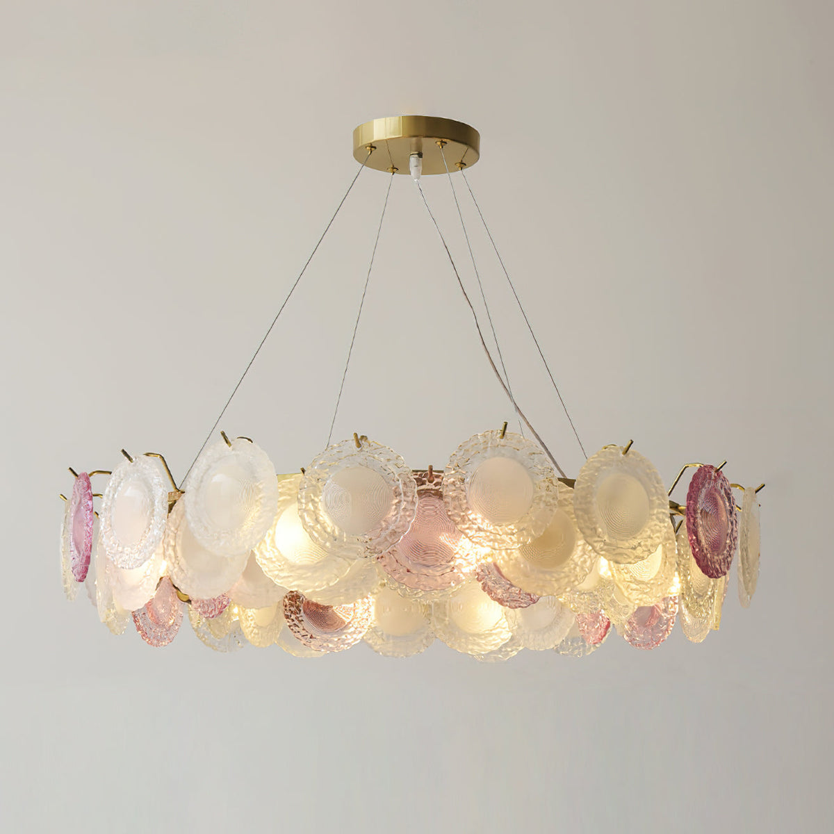 Wide view of a Clérachic pendant lit, with overlapping pink, clear and frosted glass discs round the gold frame.