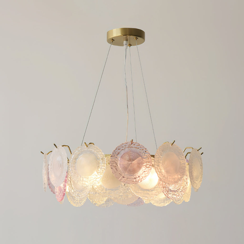 A Clérachic pendant of pink and frosted glass discs, lit, with a gentle glow from the bulbs inside the ring.