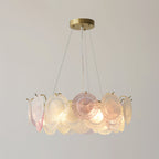 A Clérachic pendant of pink and frosted glass discs, lit, with a gentle glow from the bulbs inside the ring.