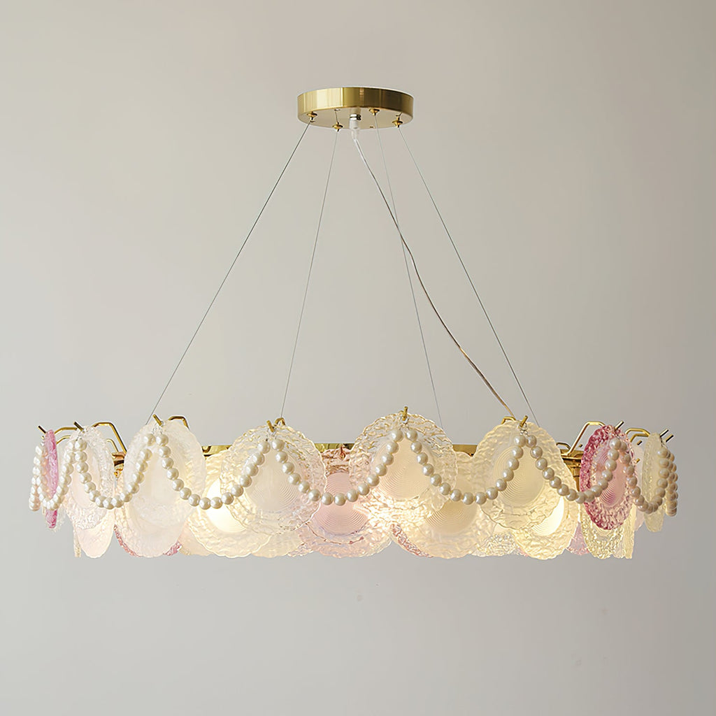 Wide Clérachic pendant with pearl swags, lit, with a ring of frosted glass discs and a few pink ones on a grey wall.