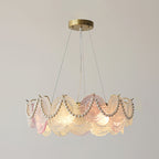 Clérachic pendant with pearls looped over its glass discs, lit, with a pink disc near the centre of the ring.