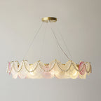 A lit Clérachic pendant with looped pearls and pink and frosted glass discs on a grey backdrop.