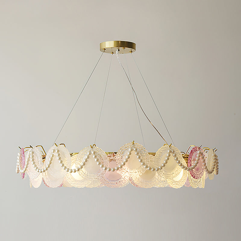 A lit Clérachic pendant with looped pearls and pink and frosted glass discs on a grey backdrop.