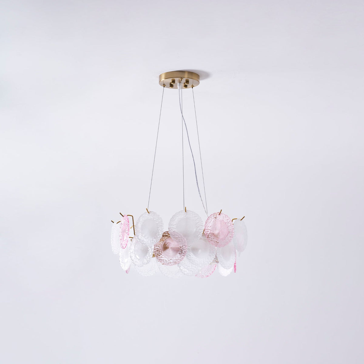 A smaller Clérachic pendant of pink and frosted glass discs, seen on a pale lilac backdrop.