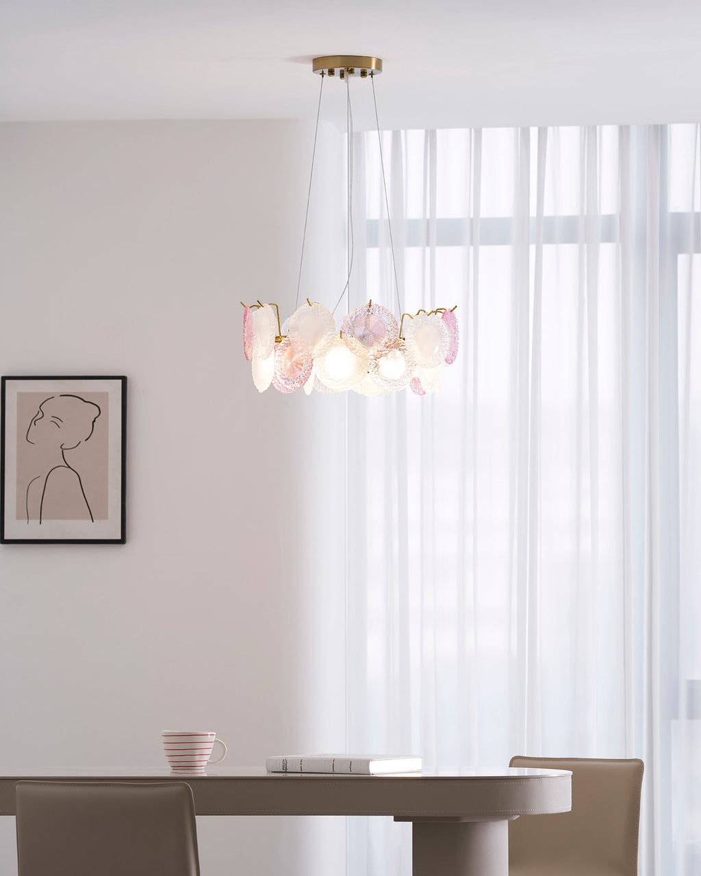 Clérachic pendant, lit, with pink and frosted glass discs, hung in a room with sheer curtains and a framed line drawing.