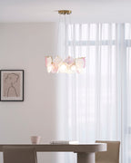 Clérachic pendant, lit, with pink and frosted glass discs, hung in a room with sheer curtains and a framed line drawing.