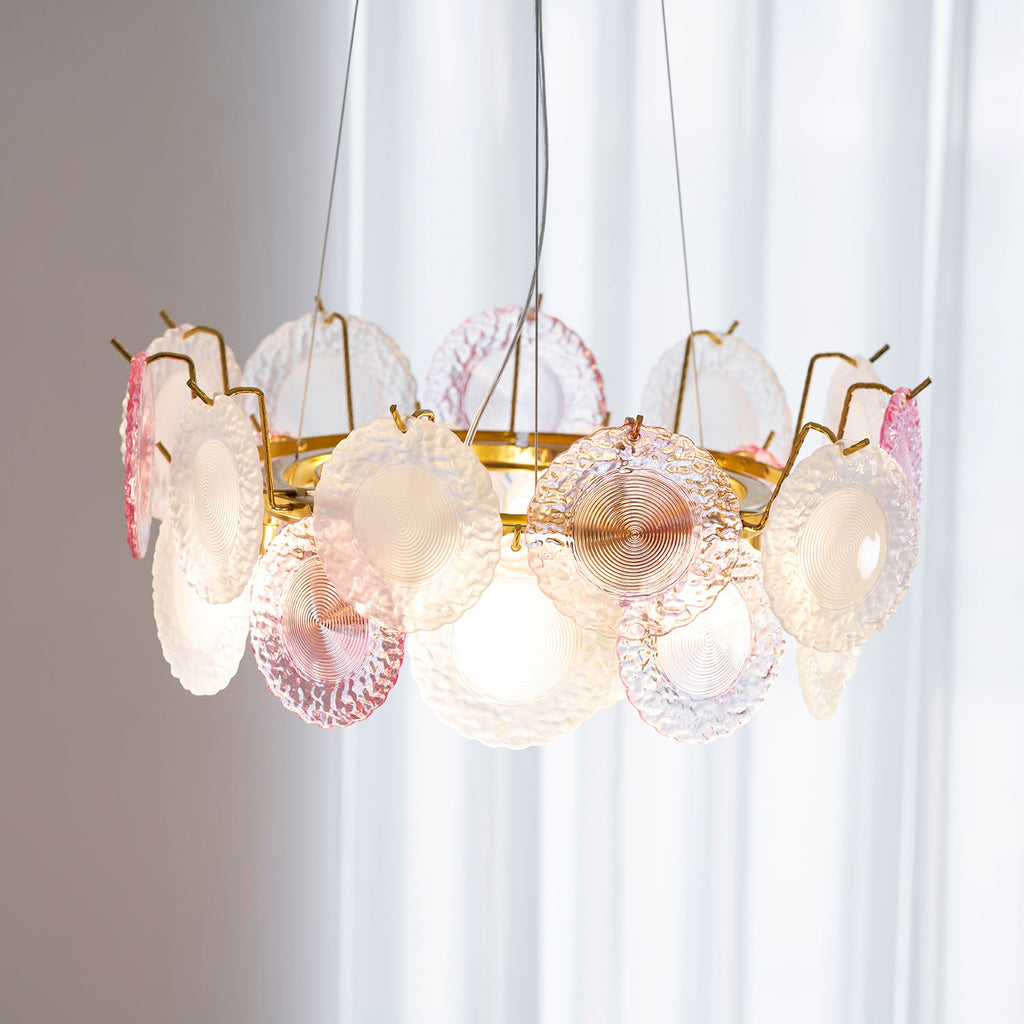 Close view of the lit Clérachic pendant from just below, showing the gold frame, the hooks and the glass discs.