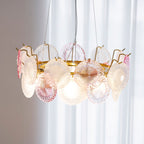 Close view of the lit Clérachic pendant from just below, showing the gold frame, the hooks and the glass discs.