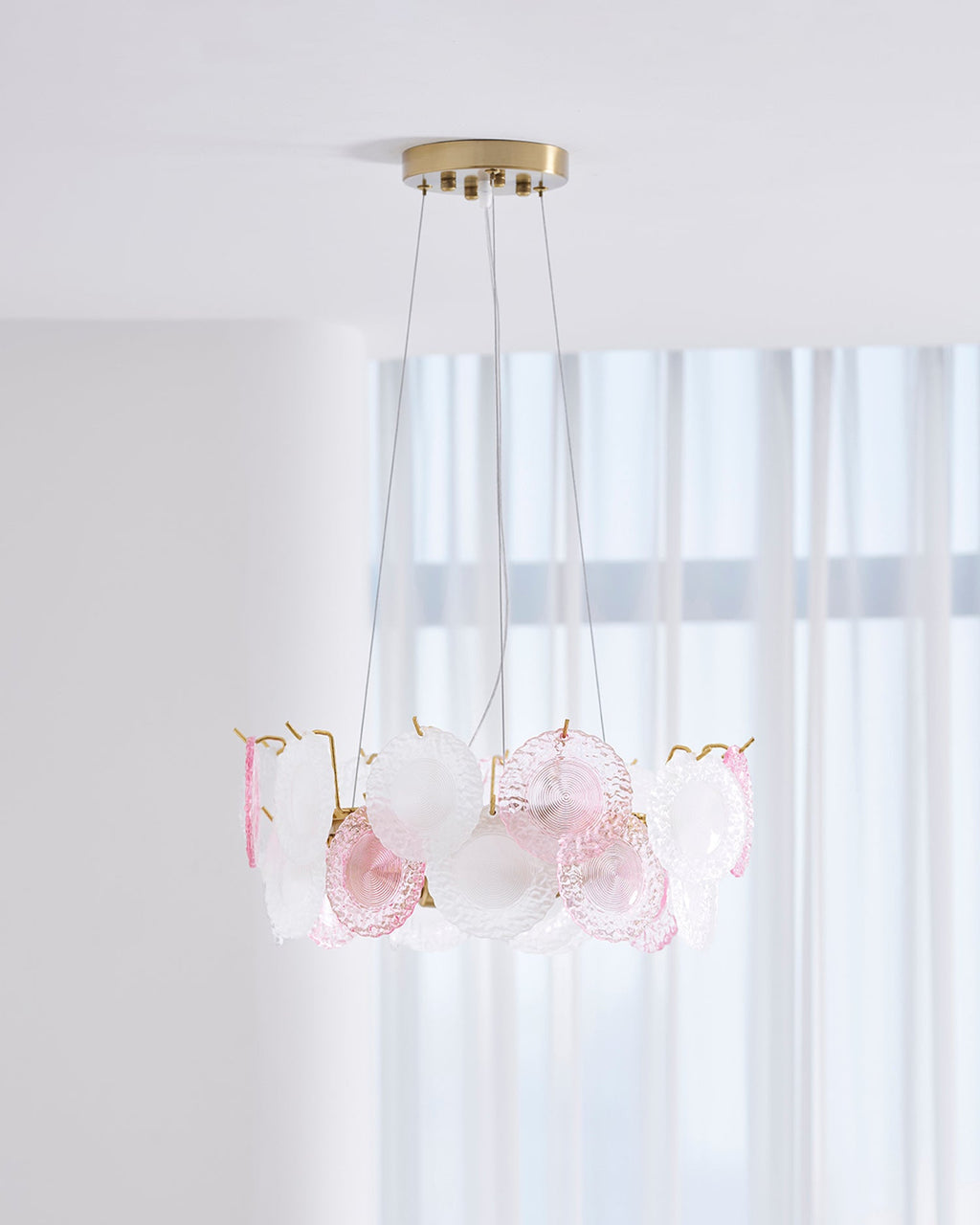 Clérachic pendant with pink and frosted glass discs, seen from slightly below, in front of tall white curtains.