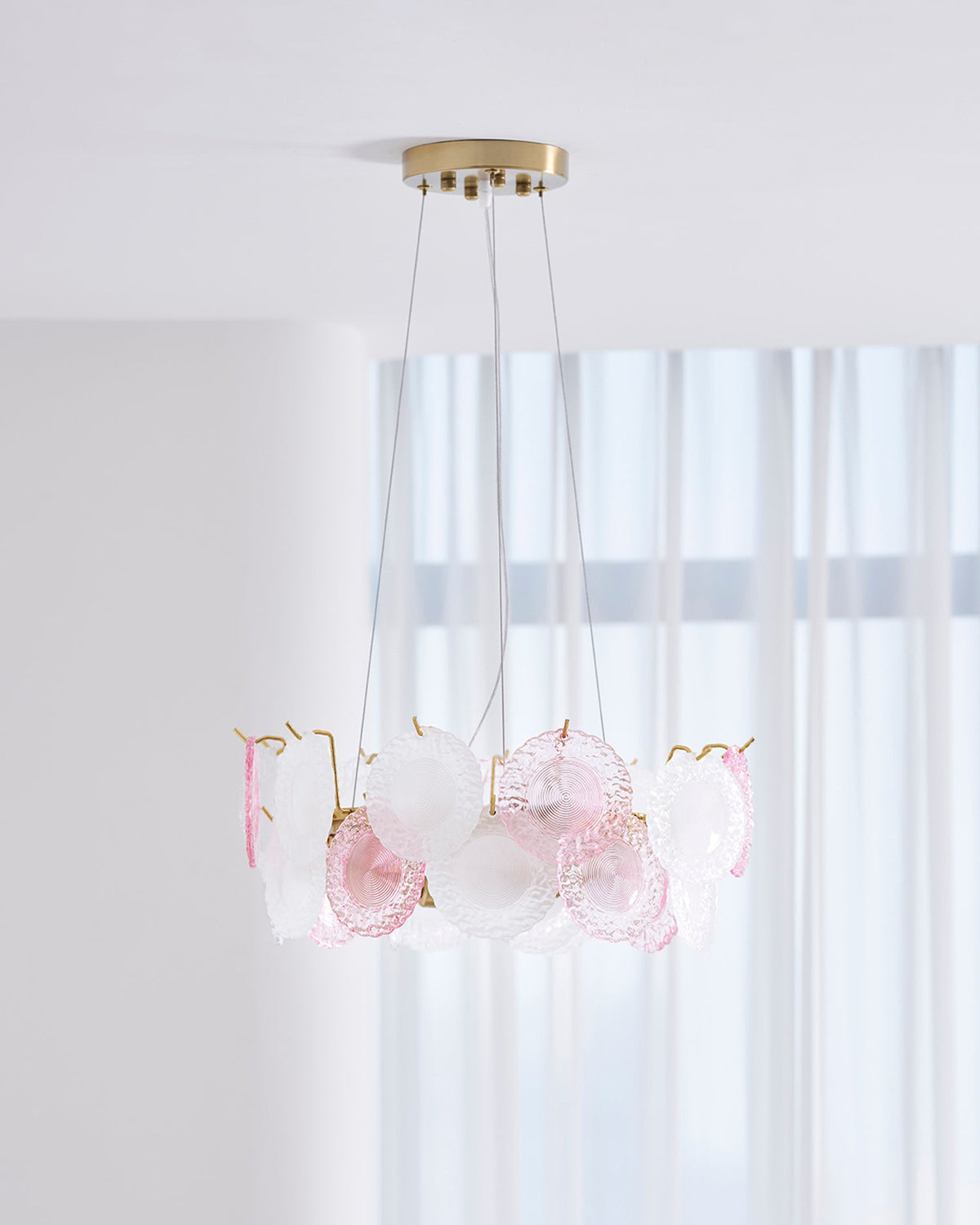 Clérachic pendant with pink and frosted glass discs, seen from slightly below, in front of tall white curtains.