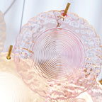 Close view of a single pink glass disc with concentric ridges and a gold hook, on this Clérachic pendant.