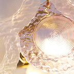 Close view of a pink disc on this Clérachic pendant, with light shining through its ridged centre.