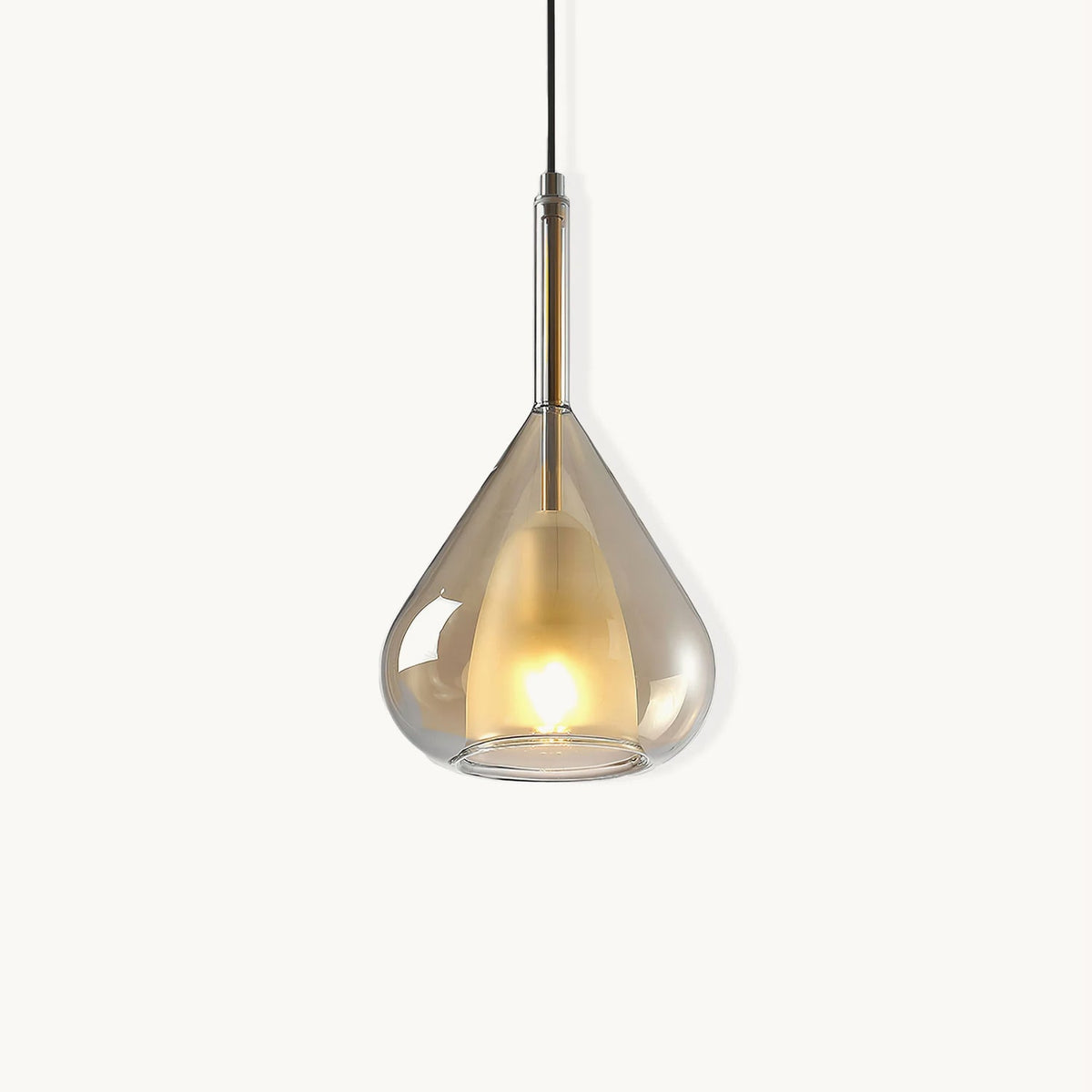 Amber glass teardrop pendant from Clérachic on a plain white backdrop, with a frosted inner shade lit warm and a slim brass stem above.
