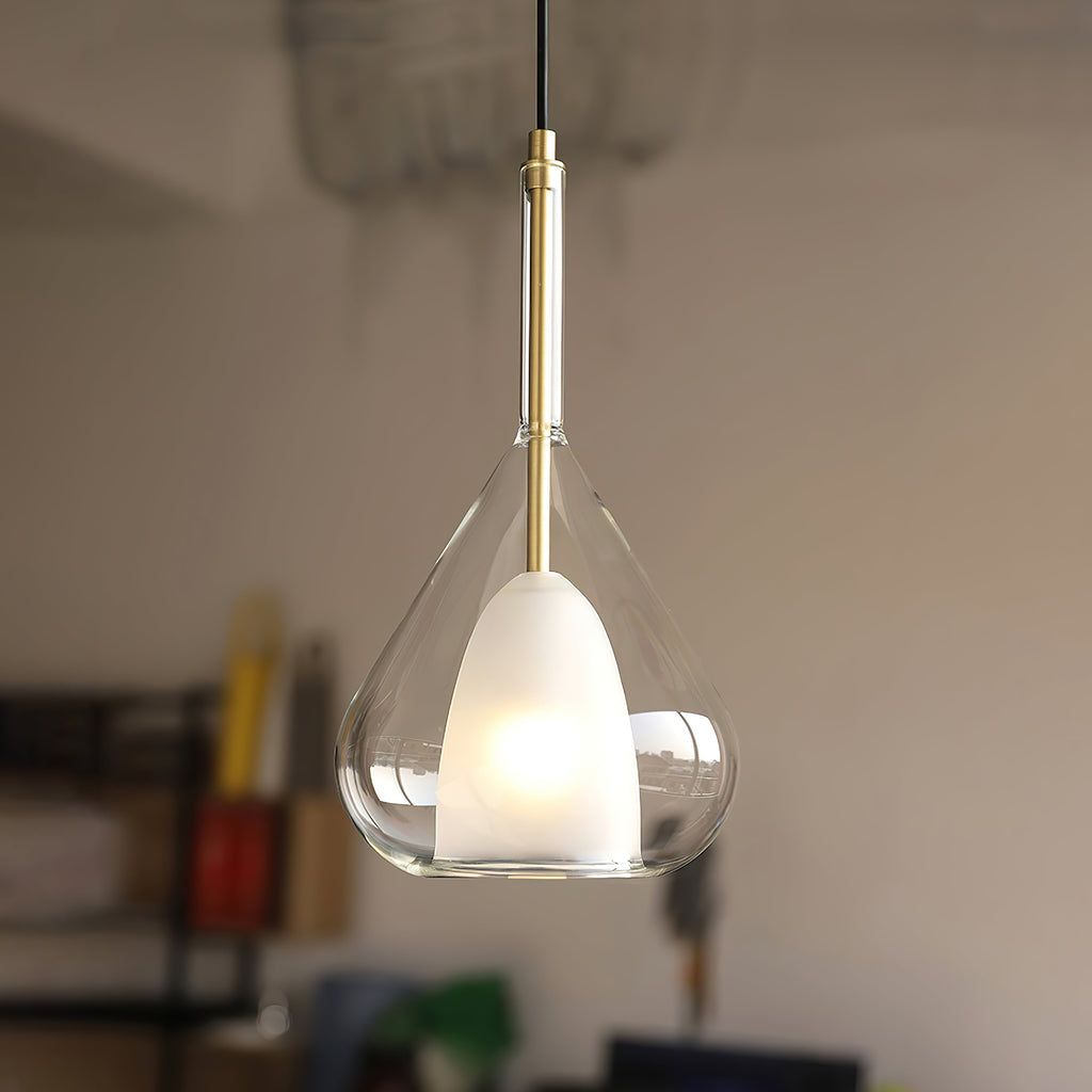 Clear glass teardrop pendant from Clérachic hanging over a softly blurred room, a frosted white inner shade glowing inside the outer glass.