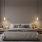 Two Clérachic glass pendants lit either side of a bed with a taupe headboard, in a calm brown-grey bedroom with bedside lamps.