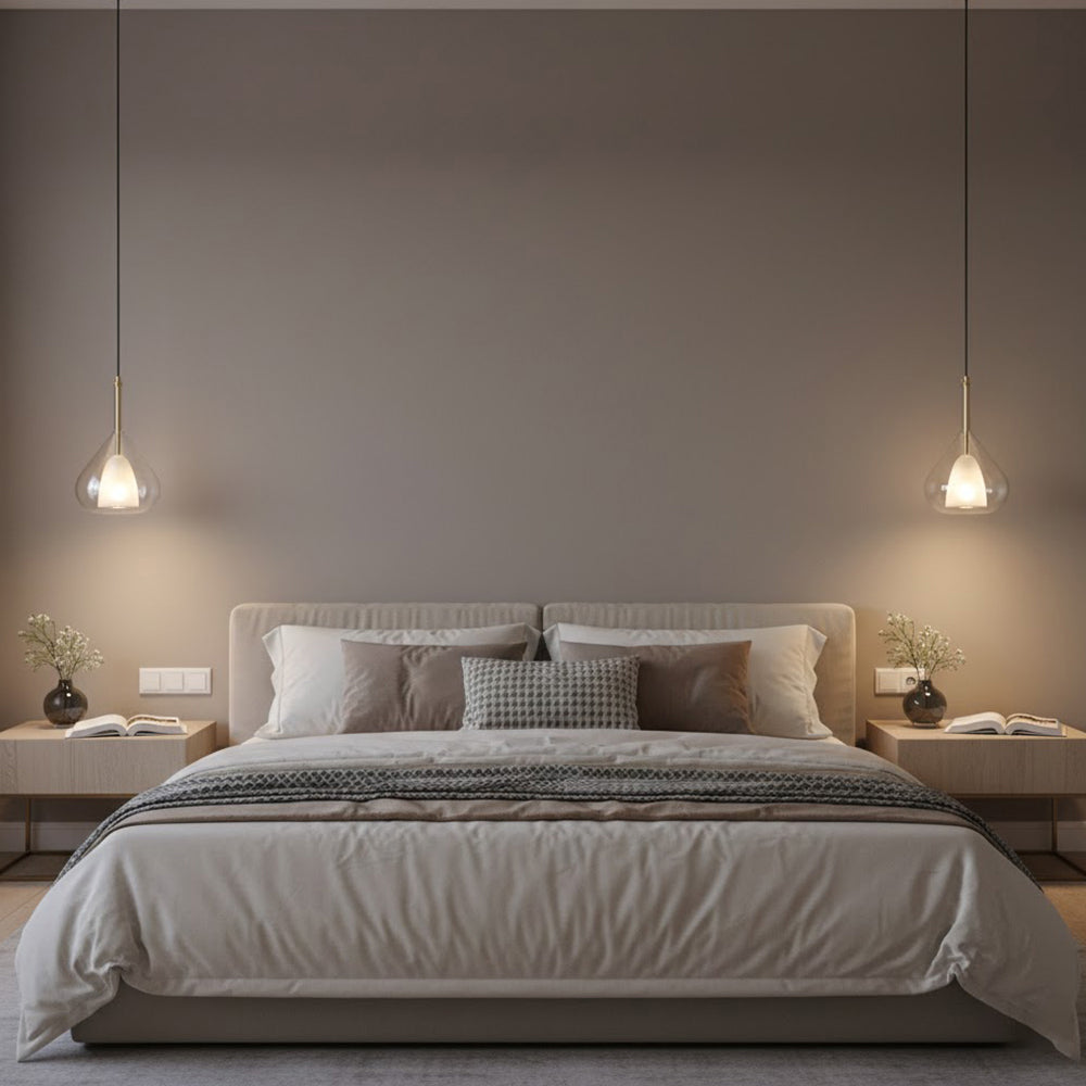 Two Clérachic glass pendants lit either side of a bed with a taupe headboard, in a calm brown-grey bedroom with bedside lamps.