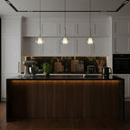 Three Clérachic glass pendants hung over a dark wood kitchen island with an under-counter glow, with white shaker cabinets behind.