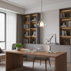 A Clérachic glass pendant lit in a home office, hanging in front of shelving with warm strip lighting and a walnut desk with an open laptop.