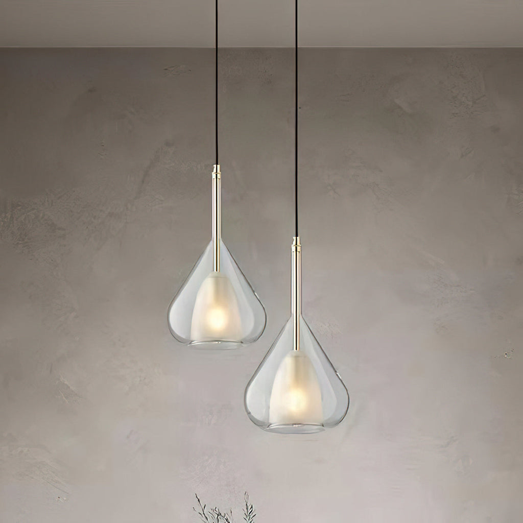 Two Clérachic clear glass pendants at different heights against a limewashed grey wall, each with a frosted inner shade and a warm glow.