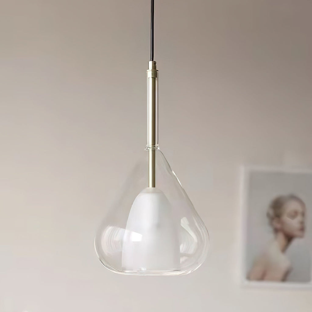 Close view of a clear glass teardrop pendant from Clérachic, with a frosted inner shade, a brass stem and black cord, against a pale wall.