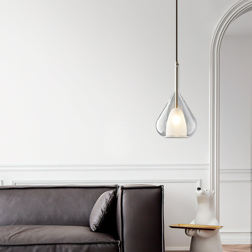 Clérachic clear glass pendant lit in a white room with an arched opening, above a dark leather sofa with a cushion.