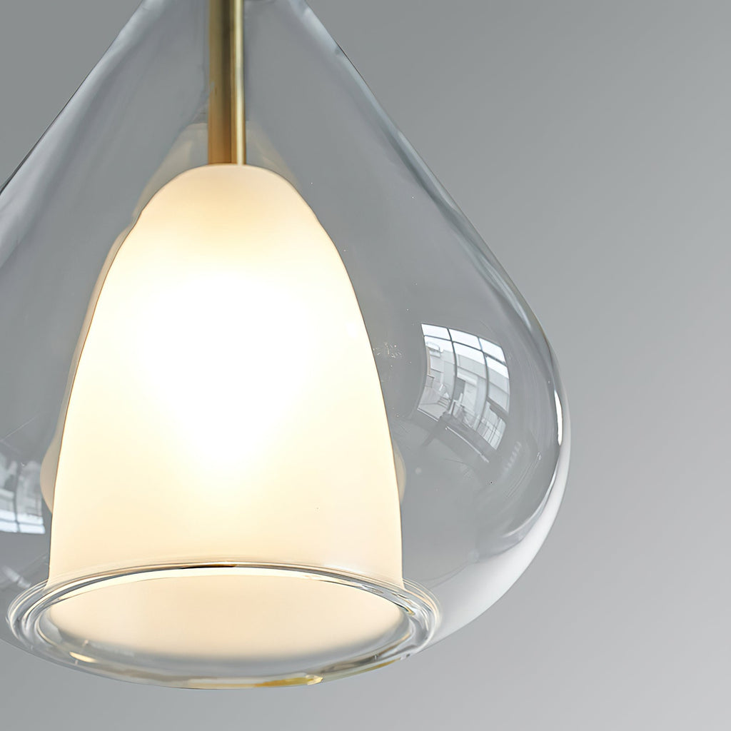 Close view of the frosted white inner shade and clear outer glass of this Clérachic pendant, with a brass stem above.