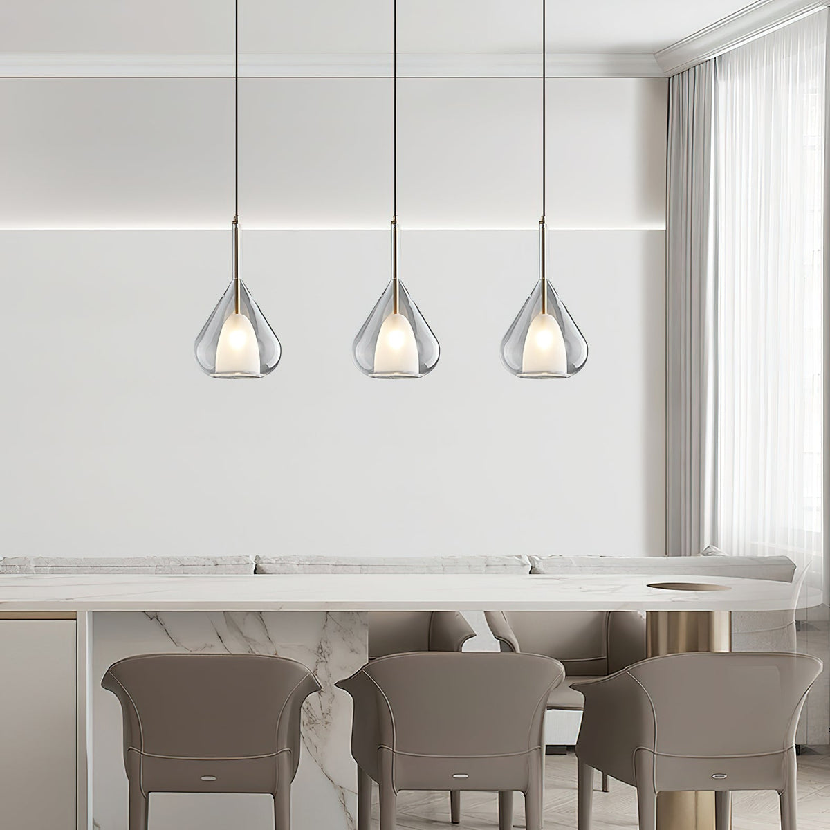 Three Clérachic clear glass pendants in a row above a marble-topped counter with taupe chairs, seen from further back.