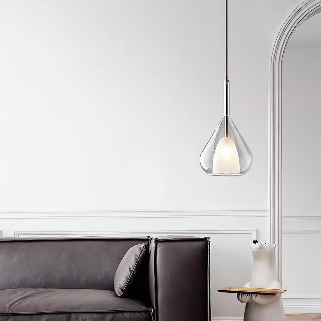 Clérachic clear glass pendant lit in front of a white arched opening, above a dark leather sofa with a cushion.