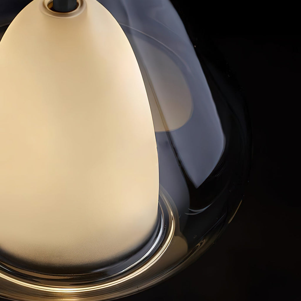 Close view of the rim of a smoke grey glass pendant from Clérachic on a black backdrop, with the frosted inner shade glowing.