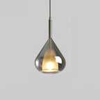 Smoke grey glass teardrop pendant from Clérachic on a pale grey backdrop, with a frosted inner shade lit warm and a dark metal stem.