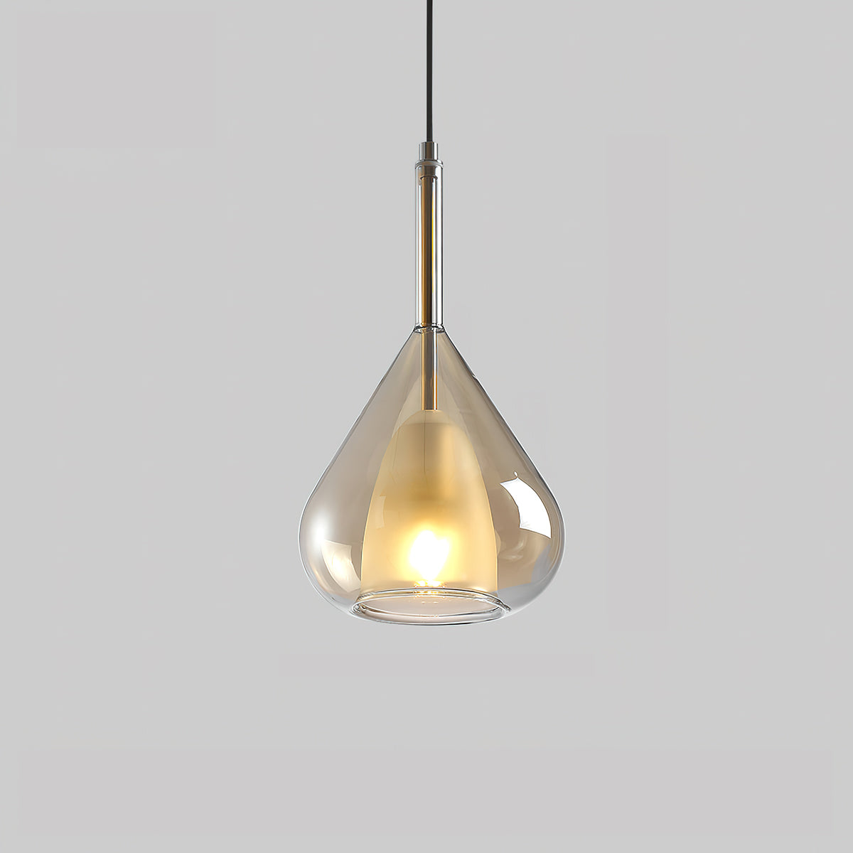 Amber glass teardrop pendant from Clérachic on a pale grey backdrop, with a lit frosted inner shade and a dark metal stem above.