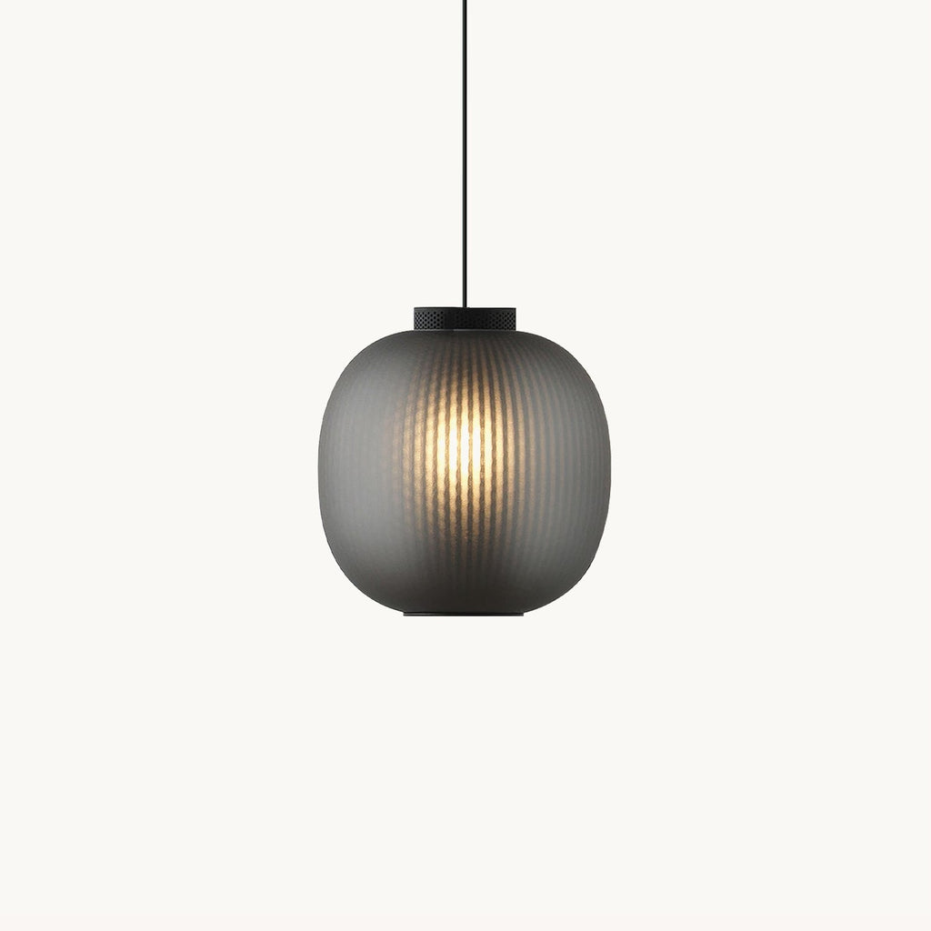 Clérachic ribbed glass pendant in smoke grey on a plain white backdrop, glowing warm through the shade with a black cap above.