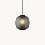Clérachic ribbed glass pendant in smoke grey on a plain white backdrop, glowing warm through the shade with a black cap above.