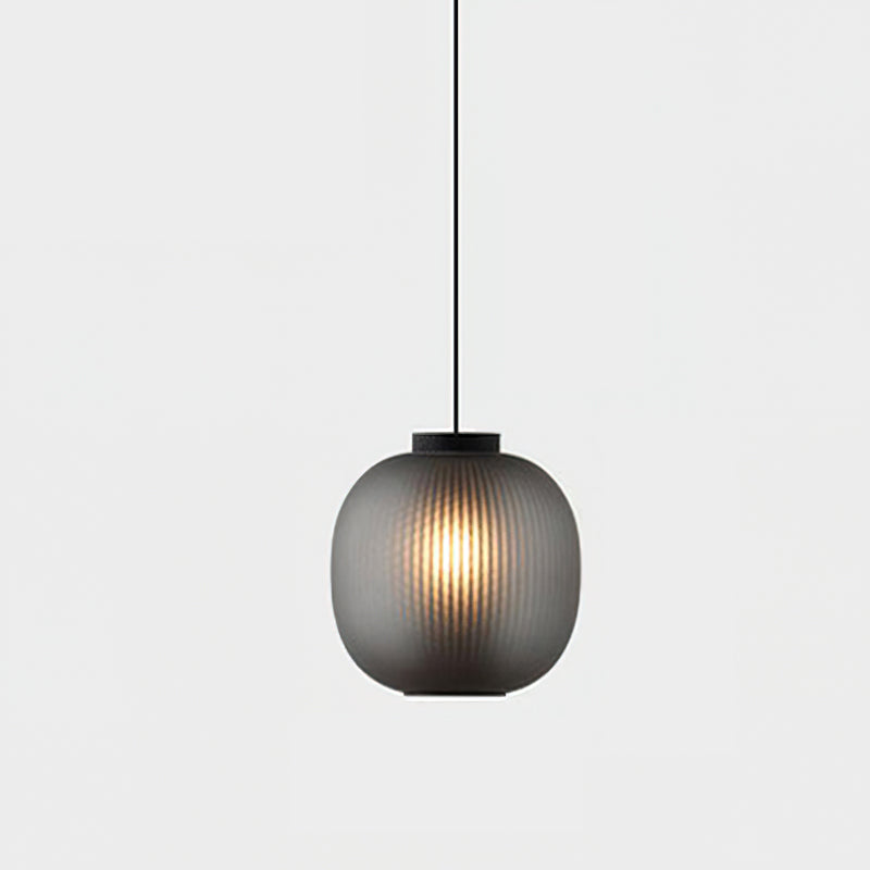 Single smoke-grey Clérachic pendant glowing softly against a pale backdrop, its ribbed glass hanging from a thin black cord.