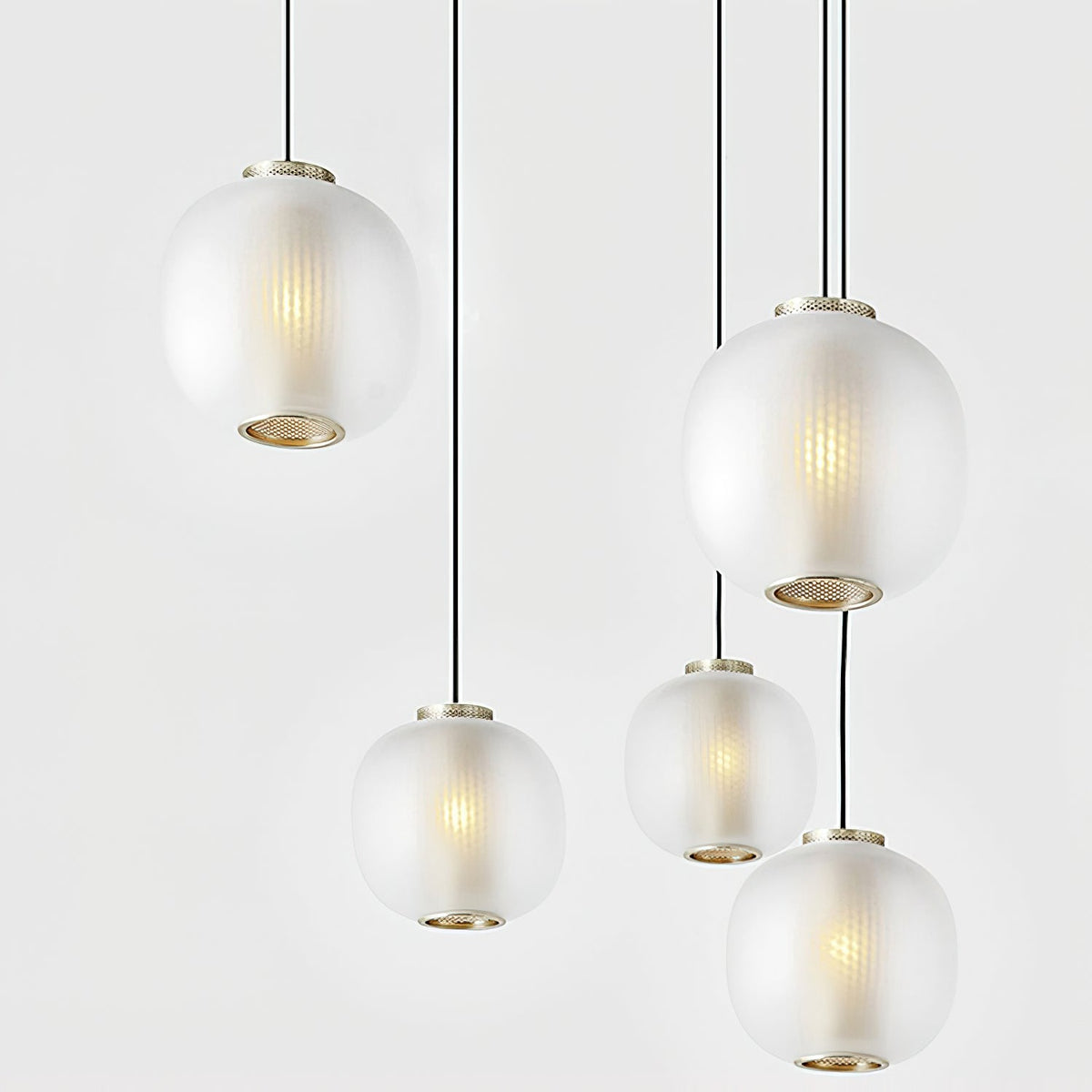 Five matte white Clérachic ribbed glass pendants of varying sizes hanging at different heights, each with a brass-toned base ring.