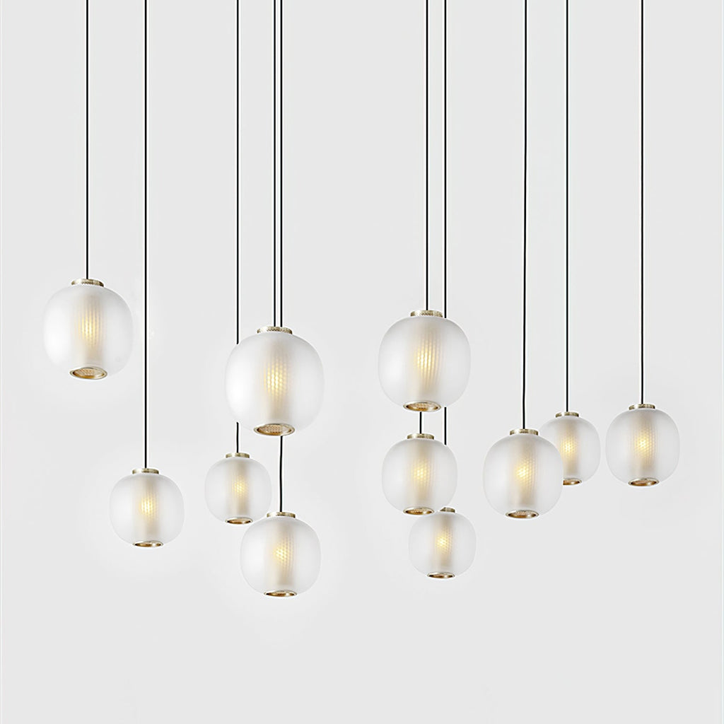 Large cluster of small matte white Clérachic pendants hanging at varied heights on long cords against a white wall.