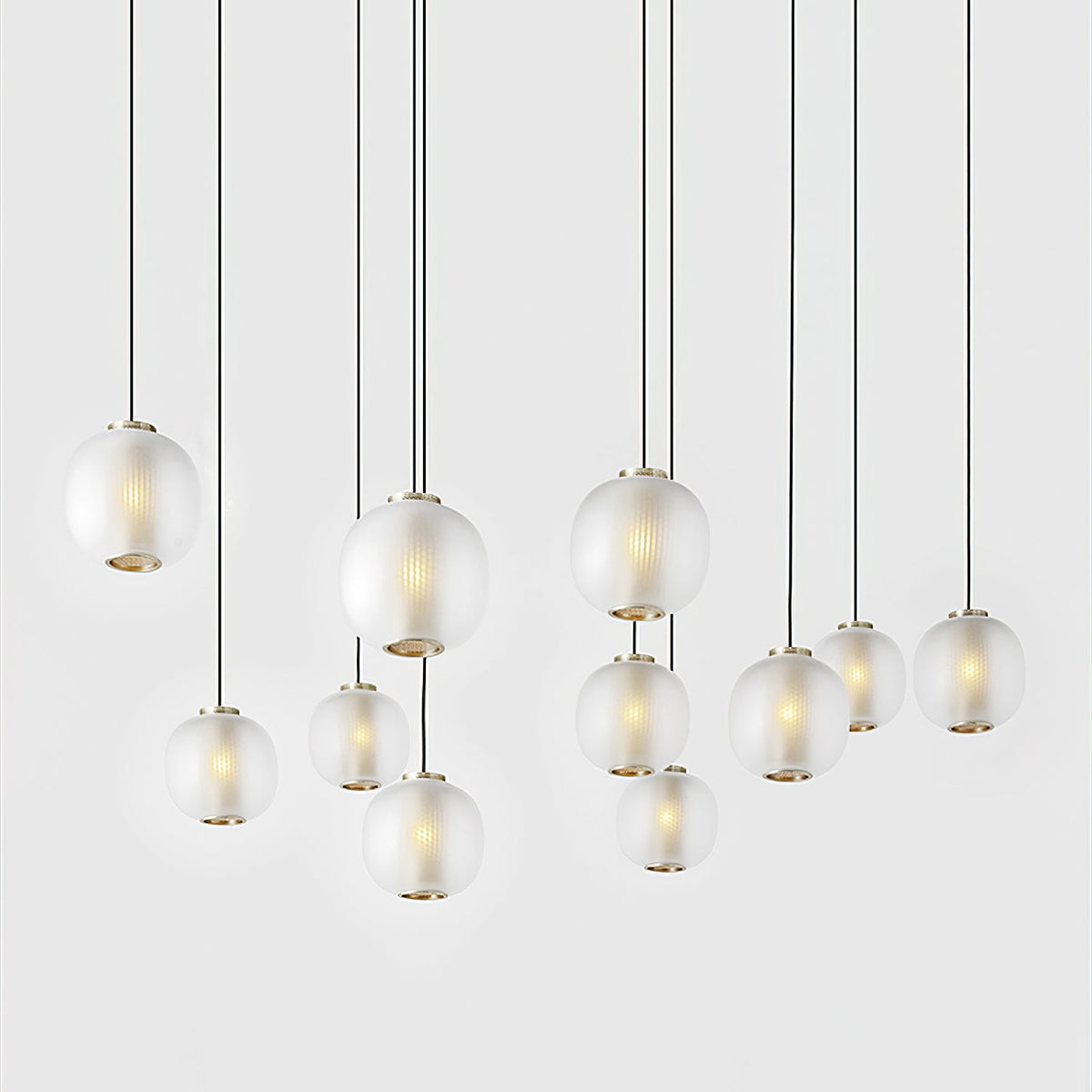 Large cluster of small matte white Clérachic pendants hanging at varied heights on long cords against a white wall.
