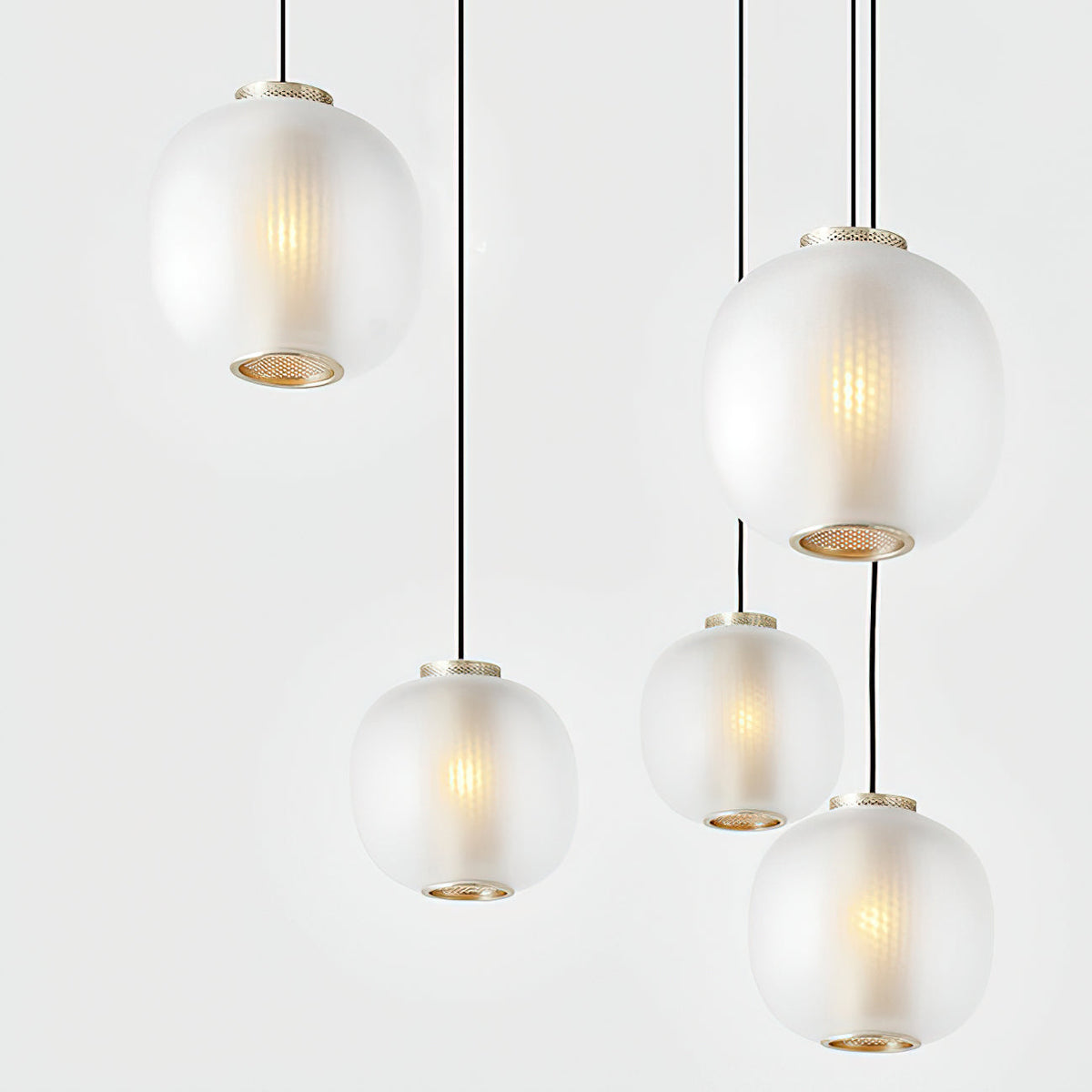 Five matte white Clérachic pendants hung close together, with brass-toned rings at the base and a warm bulb glow inside the glass.