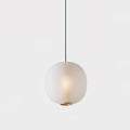 Matte white Clérachic ribbed pendant glowing against a soft grey backdrop, hanging from a slim black cord.
