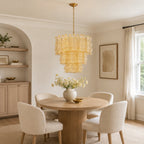 Clérachic pendant in the yellow glass finish hung over a round table of flowers and a brass bowl, with a framed print on the wall.
