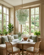 Pale green glass Clérachic pendant in a bright window nook, over a small round table with a cushioned bench and cane chairs.