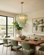 Green Clérachic pendant above a live-edge dining table with green chairs, black-framed glazed doors and a garden beyond.
