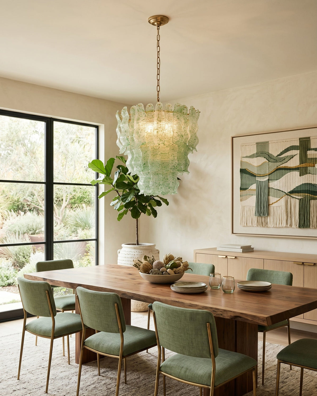 Green Clérachic pendant above a live-edge dining table with green chairs, black-framed glazed doors and a garden beyond.