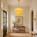 Yellow glass Clérachic pendant in a bright hallway with a dark front door, a wooden console and an arched passage.