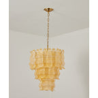 Unlit yellow Clérachic pendant with its pale amber ribbed glass tiers, hung from a brass chain against a white corner.