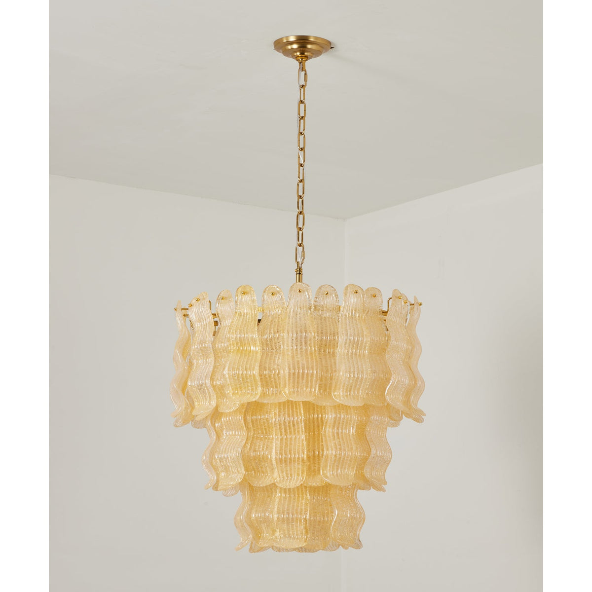 Switched-off yellow Clérachic pendant, showing the clear ribbed glass panels in three tiers under a brass ceiling plate.