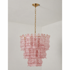 Pink speckled glass Clérachic pendant on a grey backdrop, three wavy tiers under a round brass canopy.